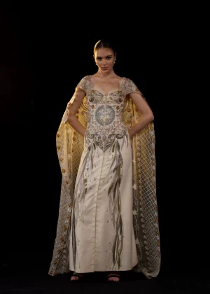 A SHEER NECK, FLOOR-LENGHT EMBROIDERED GOWN CAPE DRAPES FROM THE SHOULDERS